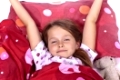 ein achtjähriges Mädchen im Bett mit Decke und Kissen und Kuscheltieren